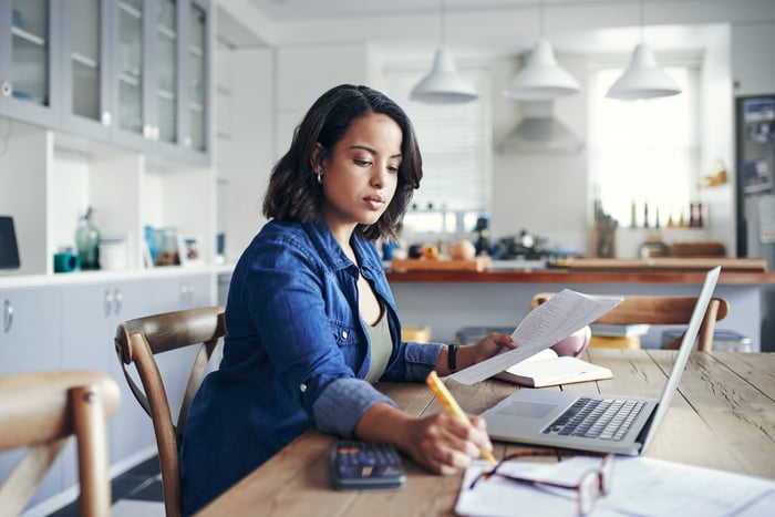 A serious person in the kitchen, holding a document and a notepad.